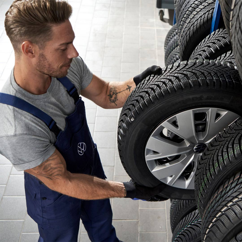 Técnico de Volkswagen elige una llanta dentro de un conjunto de neumáticos nuevos. 