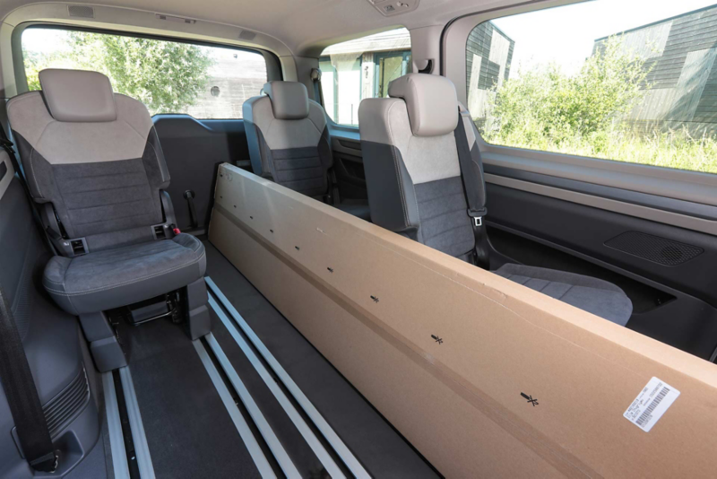 VW Multivan eHybrid lastad med en stor avlång kartong mellan sätena.