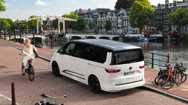 VW Multivan eHybrid parkerad i en stad bredvid vatten.