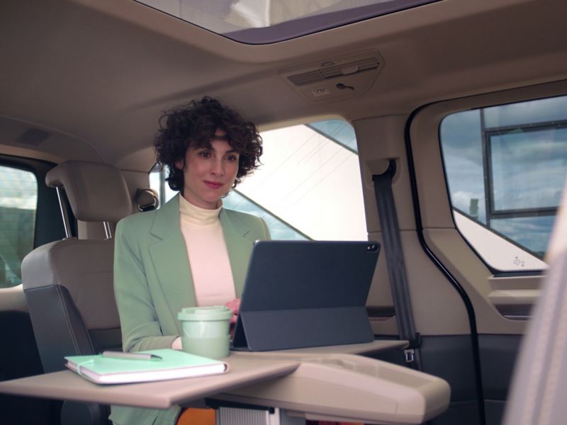 Femme dans un VW Multivan en train de travailler sur son ordinateur sur la table multifonction