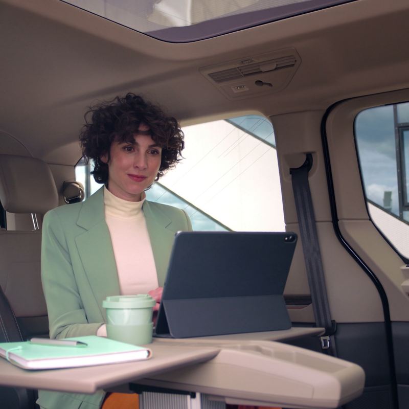 Femme dans un VW Multivan en train de travailler sur son ordinateur sur la table multifonction