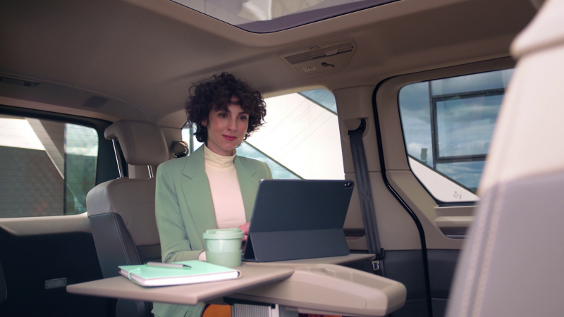 Femme dans un VW Multivan en train de travailler sur son ordinateur sur la table multifonction