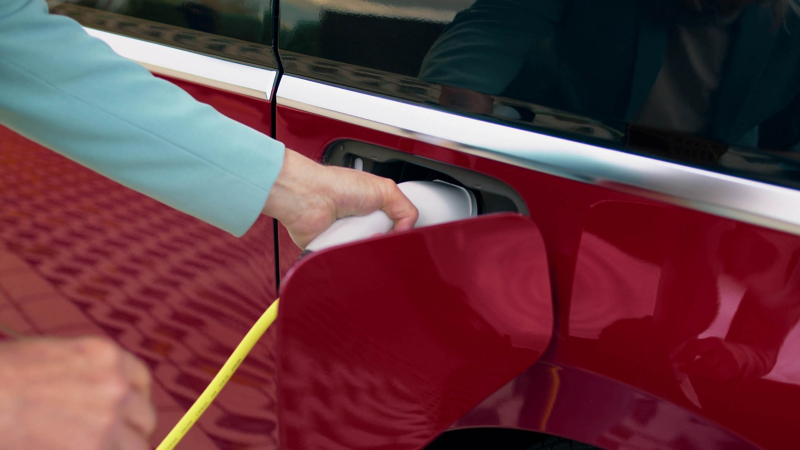 A couple walking past a VW PHEV that is being charged from a public charging station