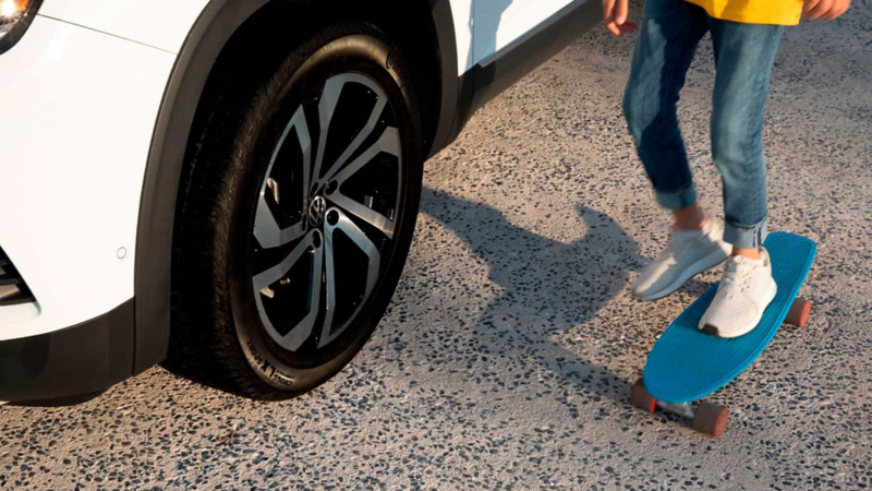 Imagen de la llanta de una camioneta SUV de Volkswagen con adolescente patinando.