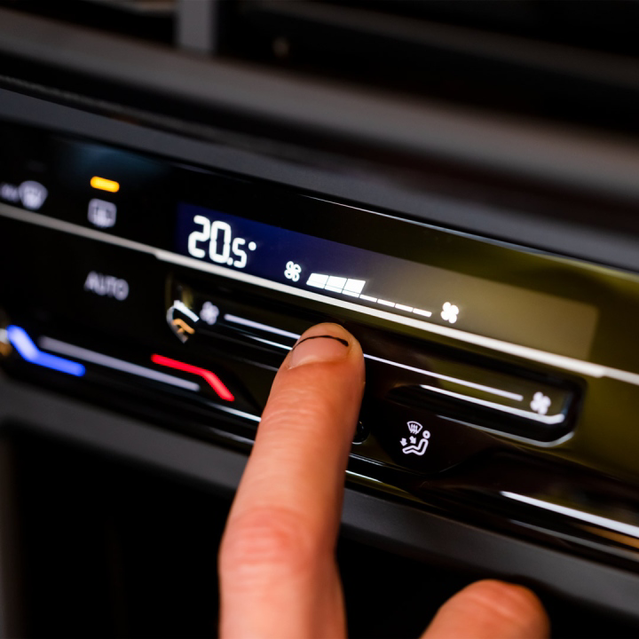 Dedo de conductor controla el panel de aire acondicionado en Volkswagen Nivus 2024, versión Highline. 
