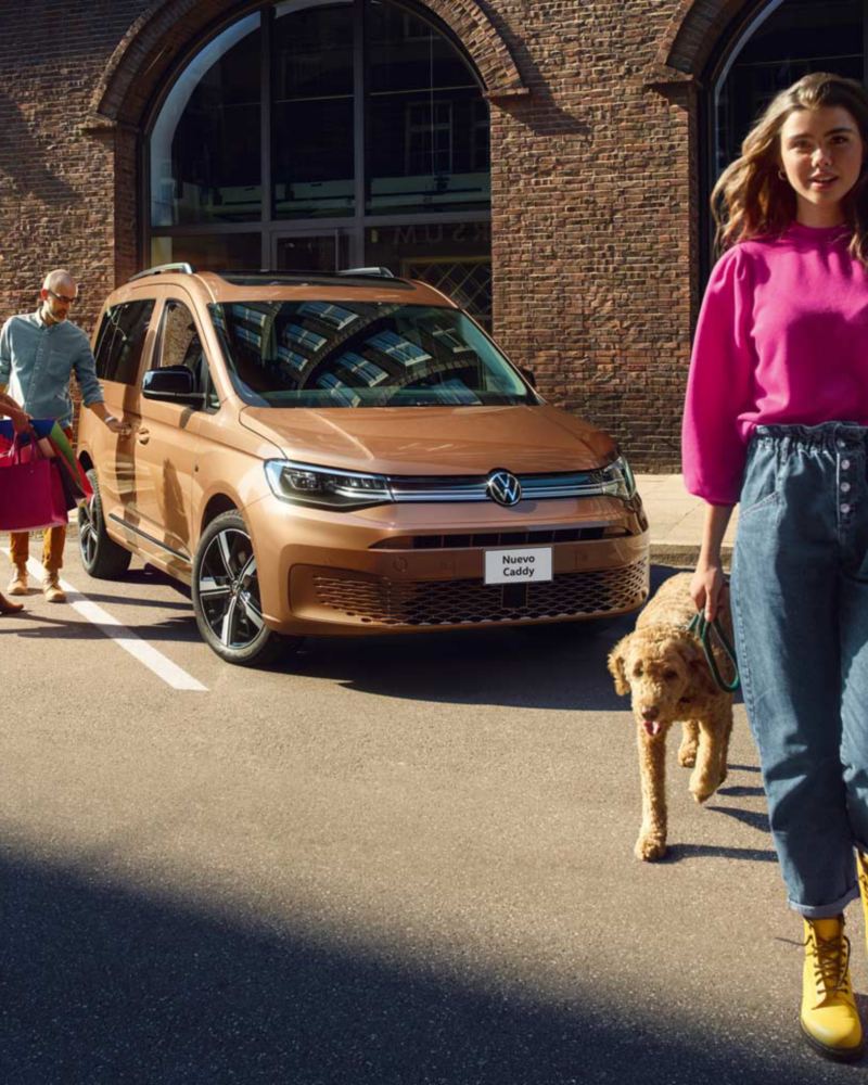 Nuevo Caddy de Volkswagen - Camioneta para pasajeros en color bronce con familia que cierra puerta.