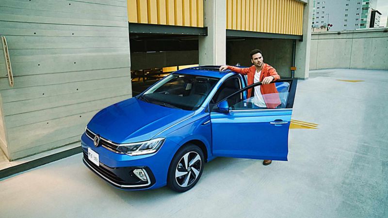 Virtus 2024 en color azul, con joven conductor a punto de abordar el auto sedán de Volkswagen. 