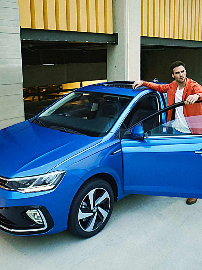 Virtus 2024 en color azul, con joven conductor a punto de abordar el auto sedán de Volkswagen. 