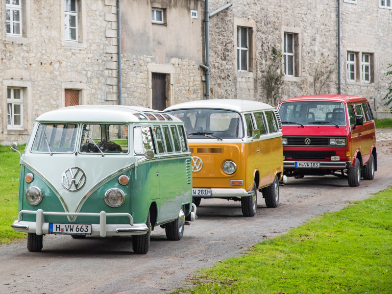 Drei VW Busse fahren eine Landstraße entlang.