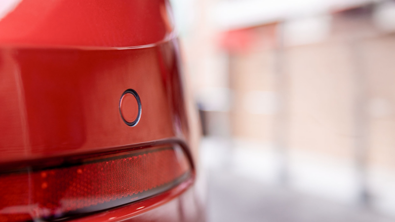 Volkswagen Polo de color rojo a las afueras de una casa con motociclistas atrás del vehículo.