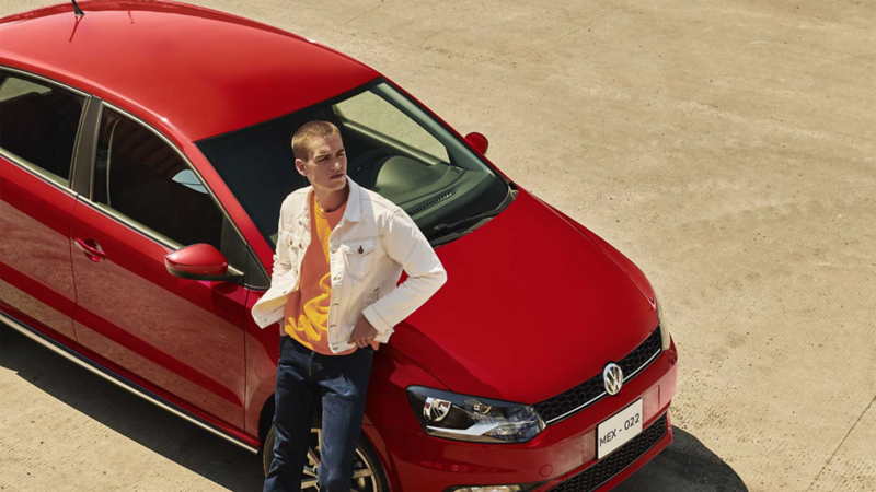 Auto Polo Volkswagen. Versión Comfortline con hombre joven sentado en cofre. 