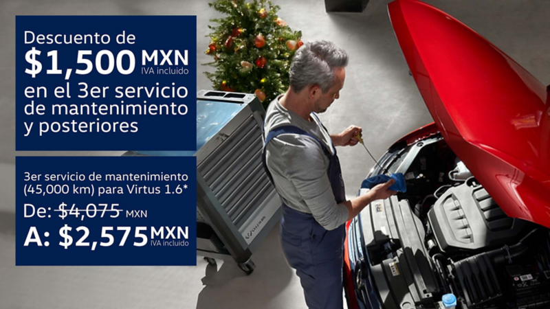 Técnico de Volkswagen revisa nivel de aceite de auto rojo con árbol de navidad al fondo.