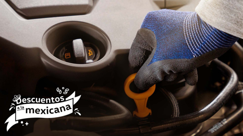 Mano enguantada revisando el nivel de aceite del motor de un coche Volkswagen con la varilla. 