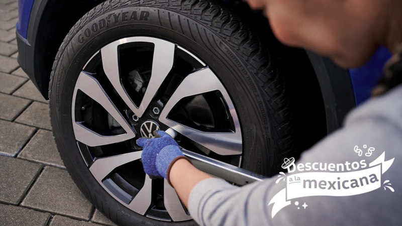 Mano enguantada ajusta el centro de una llanta Volkswagen con el logo VW.