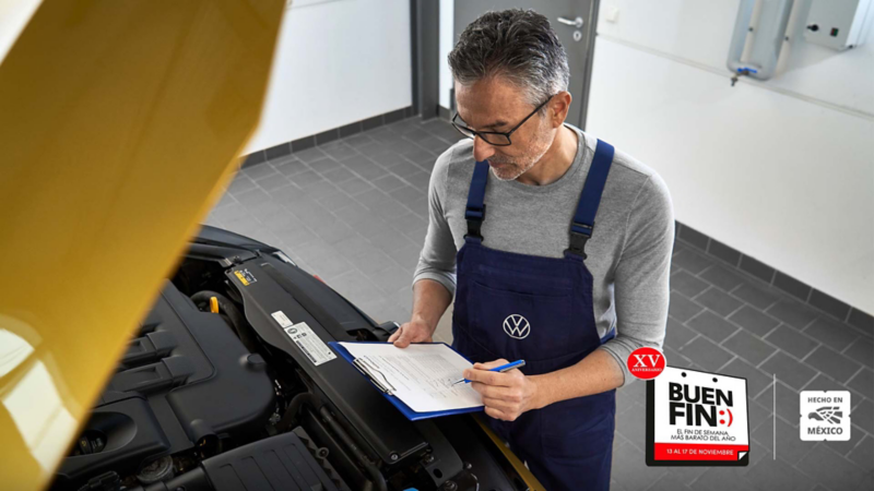 Técnico de Volkswagen revisa motor de auto amarillo y anota datos en checklist.