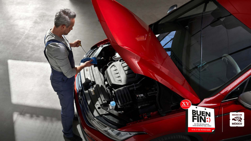 Técnico examina motor de auto deportivo rojo con cofre abierto en taller VW.