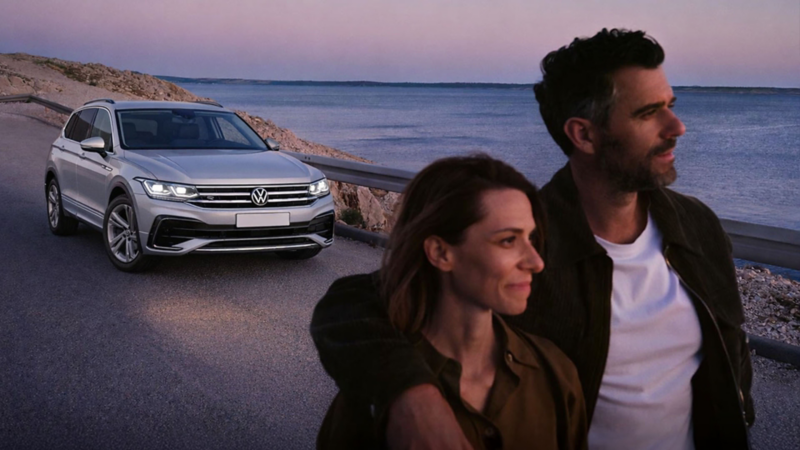 Pareja observa paisaje junto a camioneta Volkswagen color plata.