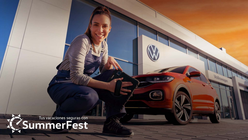 Mecánica sonríe junto a Volkswagen Taigun de color naranja, con logo de promoción Summer Fest.