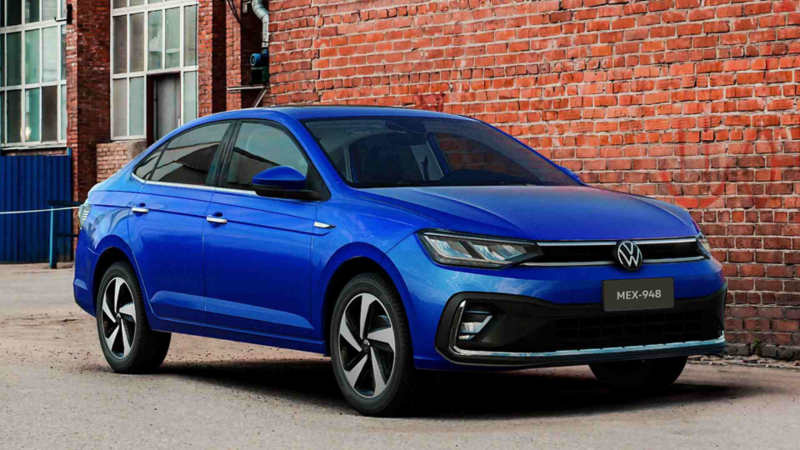 Auto familiar Nuevo Virtus 2023, en color azul. Sedán estacionado afuera de edificios de ladrillos rojos. 