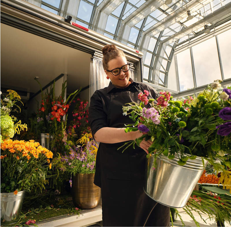Eine Floristin entnimmt frische Schnittblumen aus einem VW Crafter mit Kühlkoffer-Aufbau.