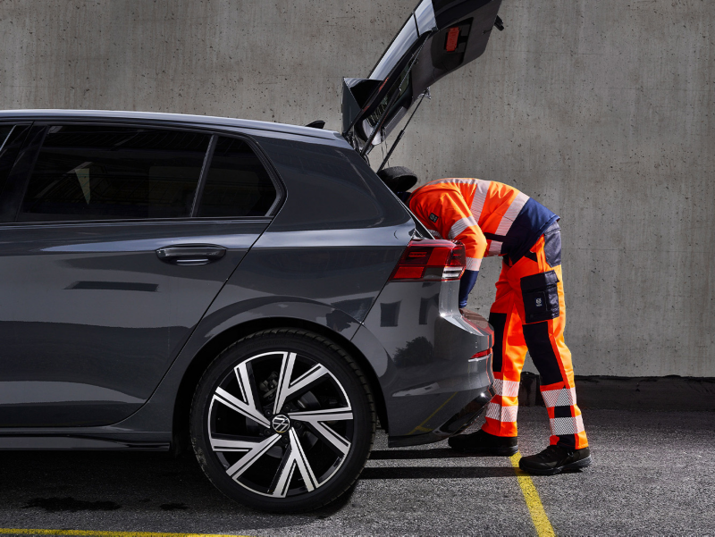 Woman with safety vest sets up warning triangle, in the background a VW ID.5 GTX