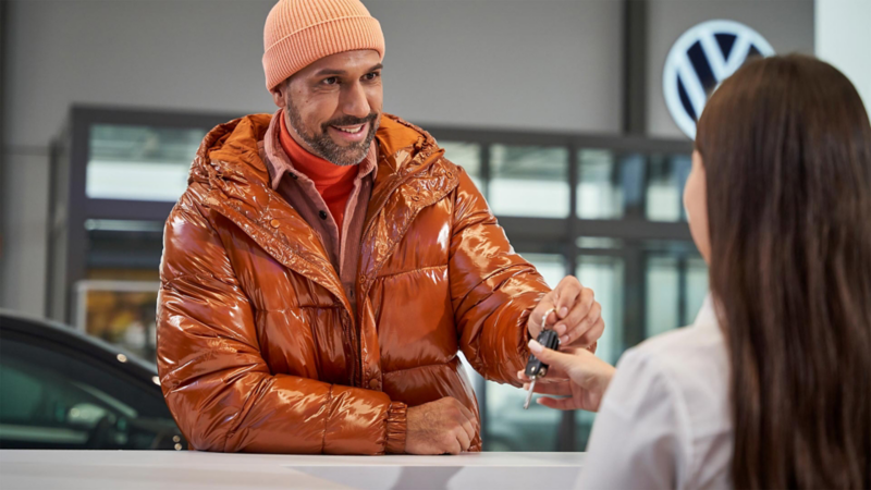 Cliente de Volkswagen entrega llaves a recepcionista en una agencia VW. 