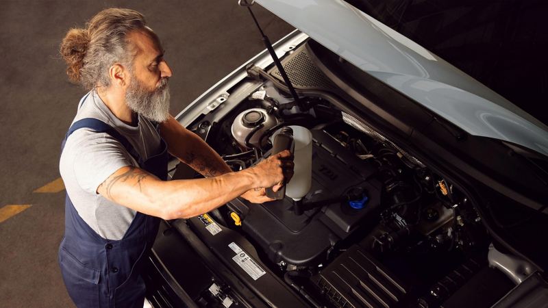 Técnico especialista realizando cambio de aceite a un auto Volkswagen.