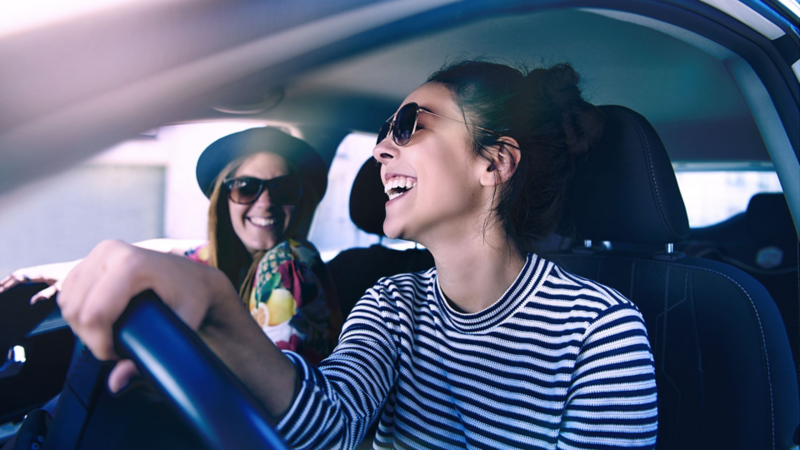 Amigas riendo dentro automóvil adquirido con crédito financiero Volkswagen para Personas con Servicios Financieros VW