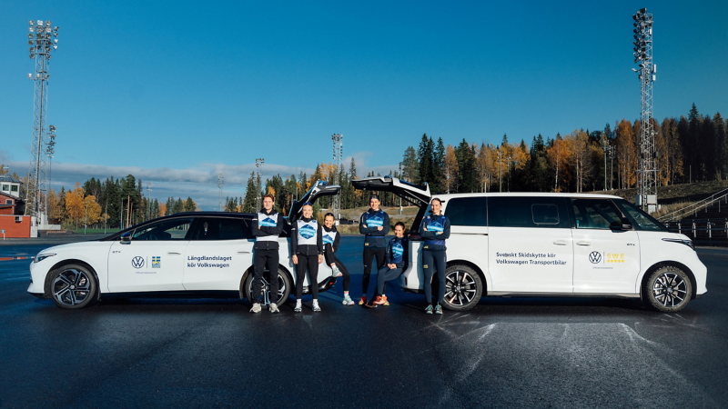 Svenska längd- och skidskyttelandslagen står framför två Volkswagen modeller