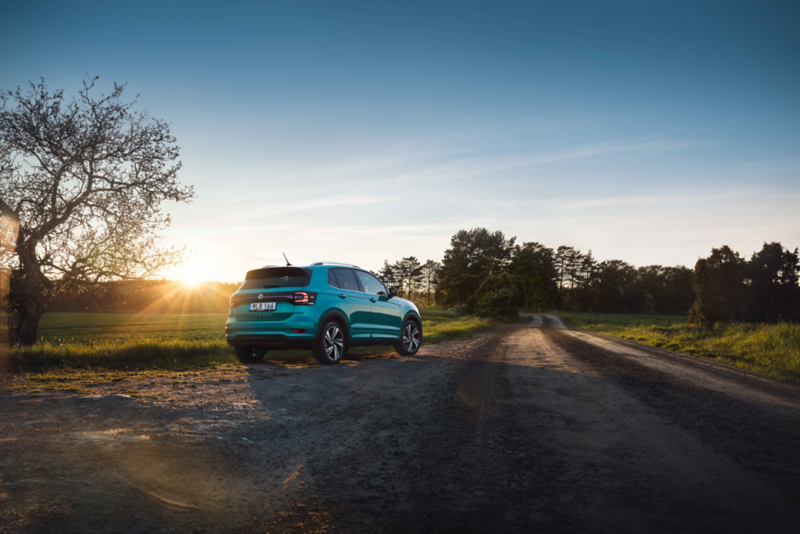 Volkswagen T-cross som kör längs landsväg på sommaren