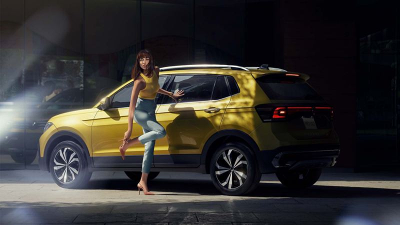 Camioneta 2022 - Nuevo T Cross de Volkswagen en color amarillo, con joven mujer que se acomoda la zapatilla.