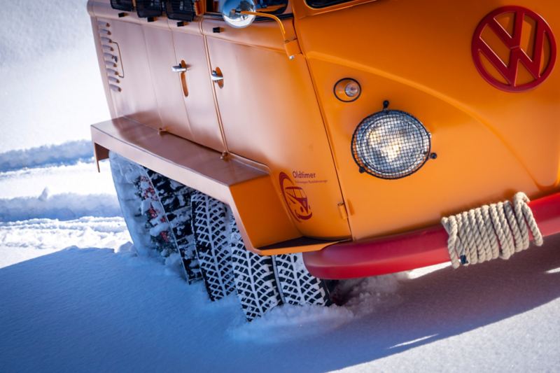 Närbild på VW T1 Caterpillar Fox Oldtimer i snö med dubbla däck fram och kedjedrivning bak