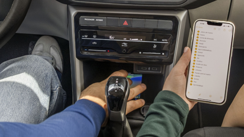 Conductor coloca celular en la zona de carga inalámbrica en el panel central de Taigun.