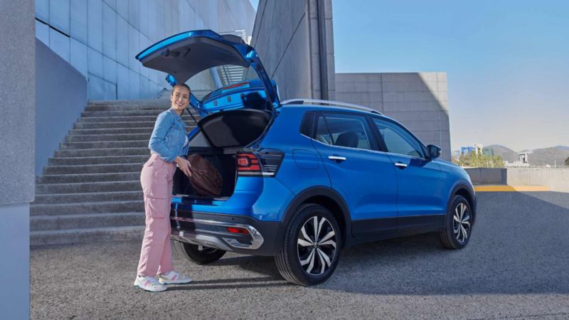 Cajuela abierta de Taigun 2023 de Volkswagen, con mujer que guarda maleta. 