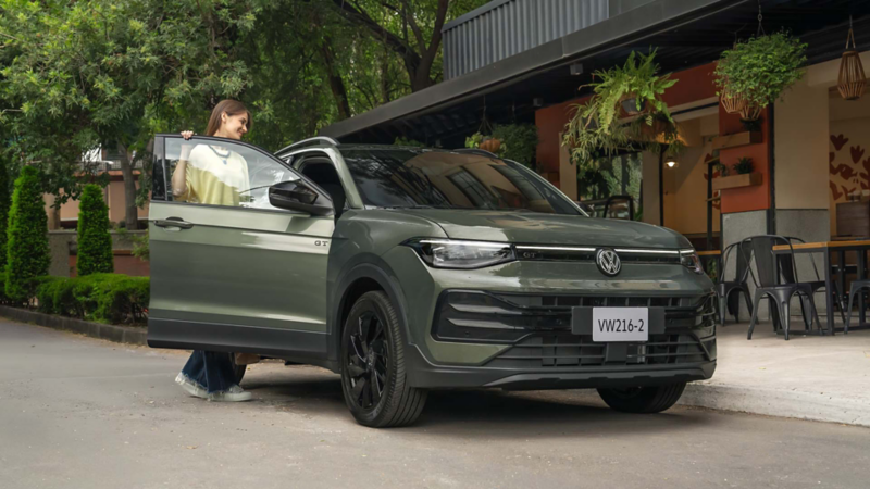 Mujer aborda SUV Taigun 2026, estacionado a las afueras de una cafetería. 