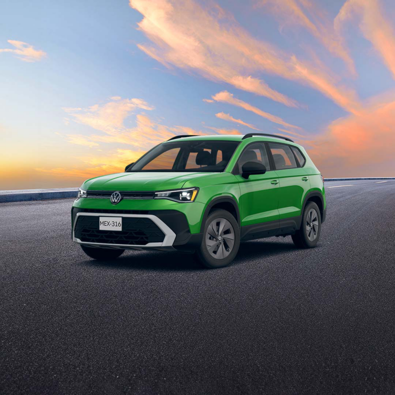 "	SUV Volkswagen Taos verde circula sobre asfalto con un cielo de atardecer al fondo."