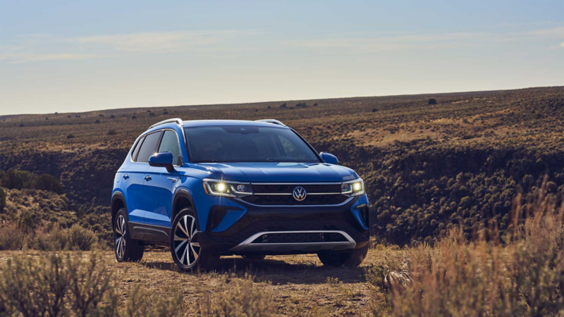 Camioneta SUV Taos 2022 en color azul dentro de una sabana a plena luz del día. 
