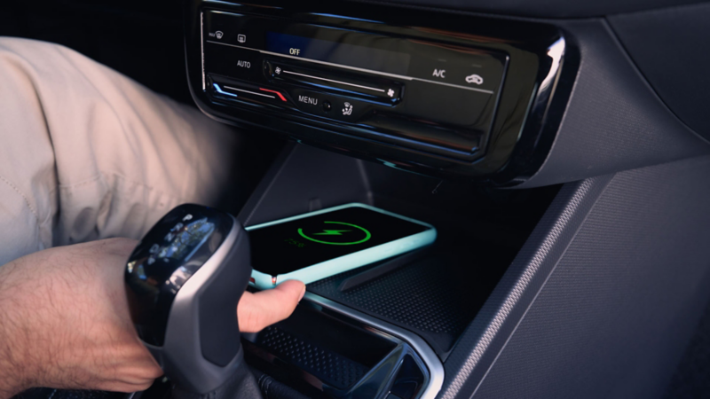 Cargador inalámbrico y panel de control de climatización en consola de Volkswagen Tera 2026.