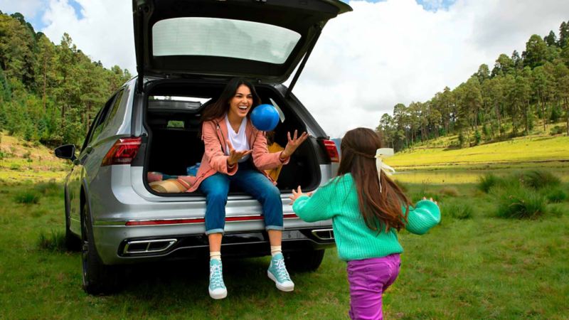 Mamá e hija juegan cerca de camioneta 2024 Tiguan de Volkswagen.