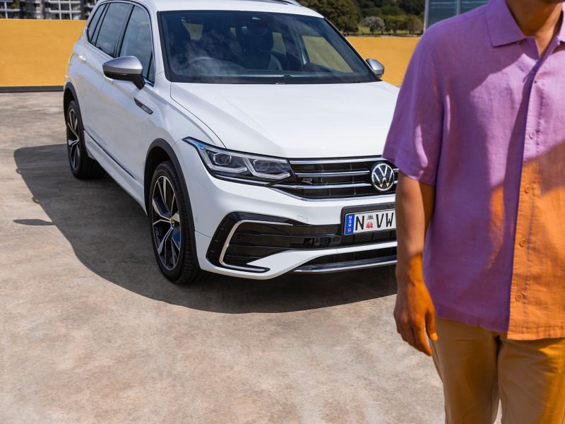 Man Walking towards the camera with Volkswagen Tiguan Allspace behind.