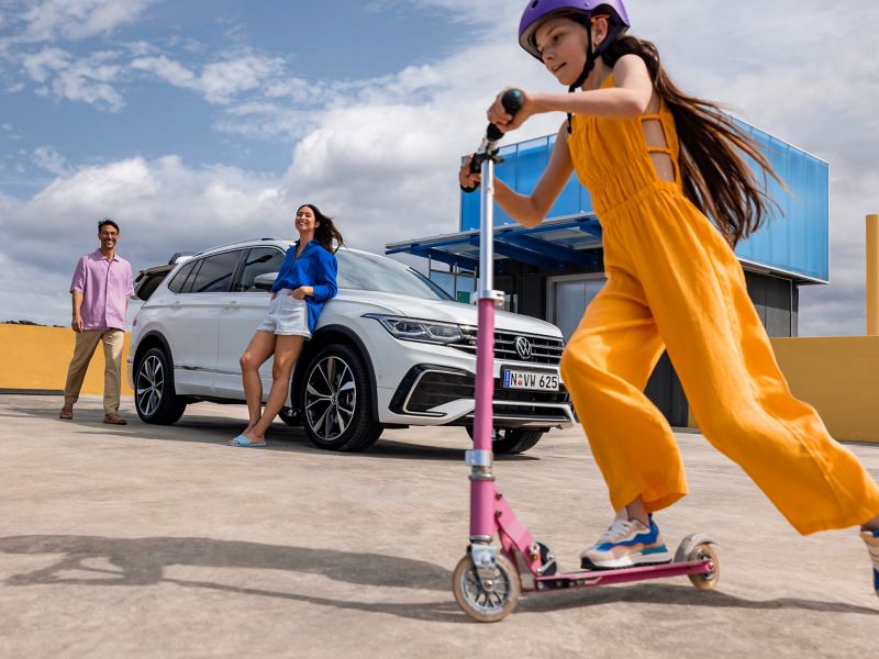 Girl playing around Volkswagen Tiguan Allspace which is parked on the rooftop.