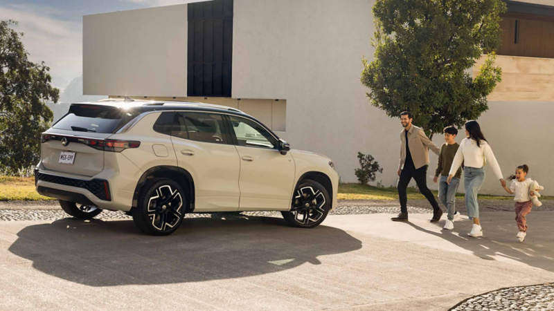 Familia camina hacia un SUVW Tiguan 2026 en color exterior blanco y techo negro. 