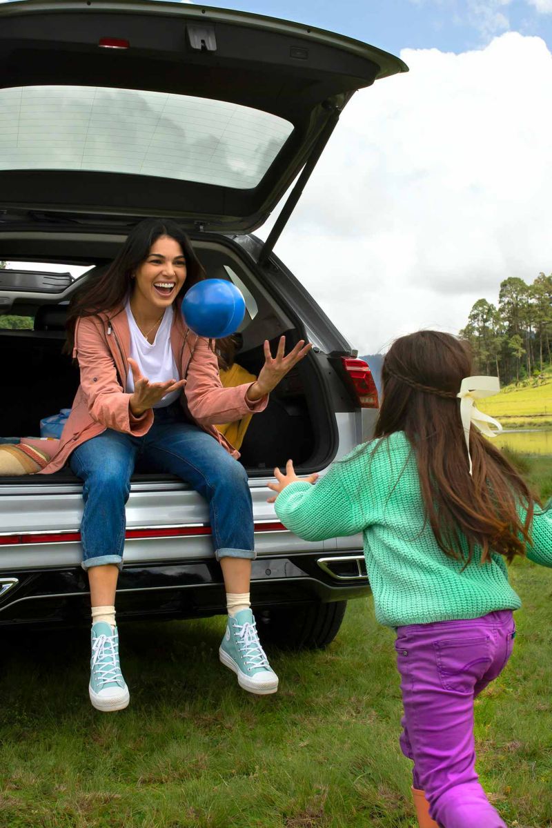 SUV Nuevo Tiguan 2022 de Volkswagen. Mamá sentada en cajuela atrapa pelota azul arrojada por una niña.