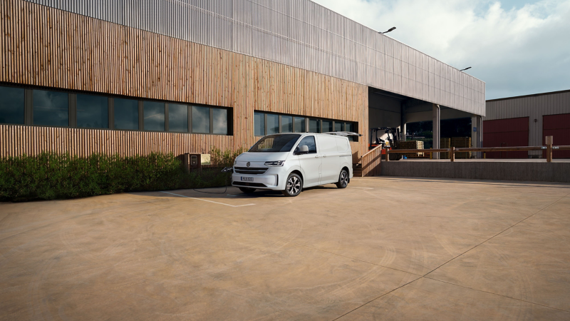 En vit VW e-Transporter Skåpbil står och laddar vid en laddstolpe