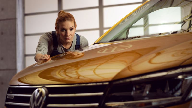 Kvinnlig mekaniker inspekterar lacken på en VW Transportbil