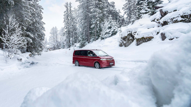 Röd VW Multivan kör på en väg i vinterlandskap