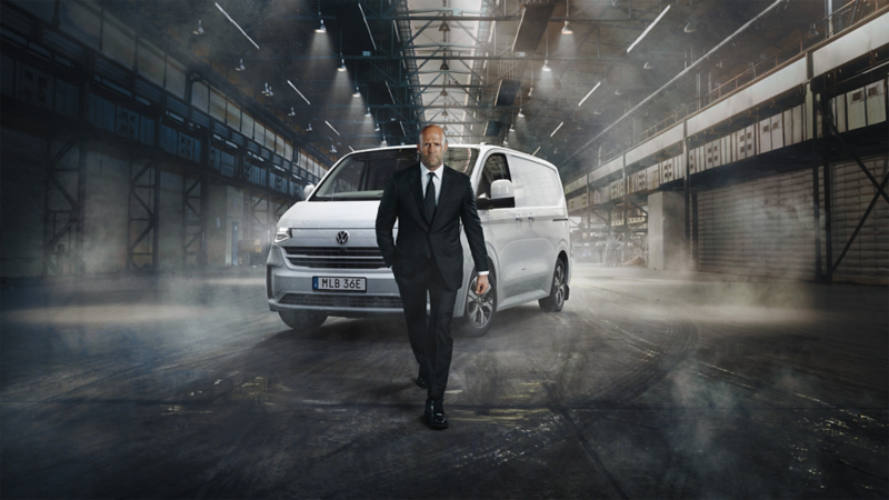 Jason Statham står framför en VW Transporter Skåp