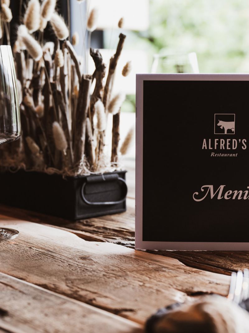 Ein stilvoll gedeckter Tisch mit Menükarte im à-la-Carte-Restaurant Alfred’s.