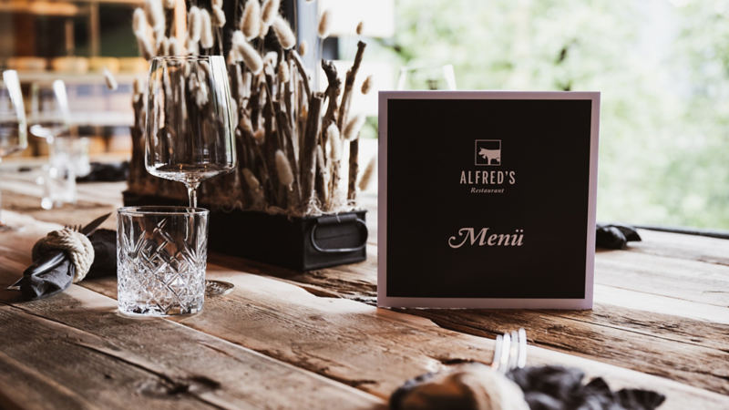 Ein stilvoll gedeckter Tisch mit Menükarte im à-la-Carte-Restaurant Alfred’s.