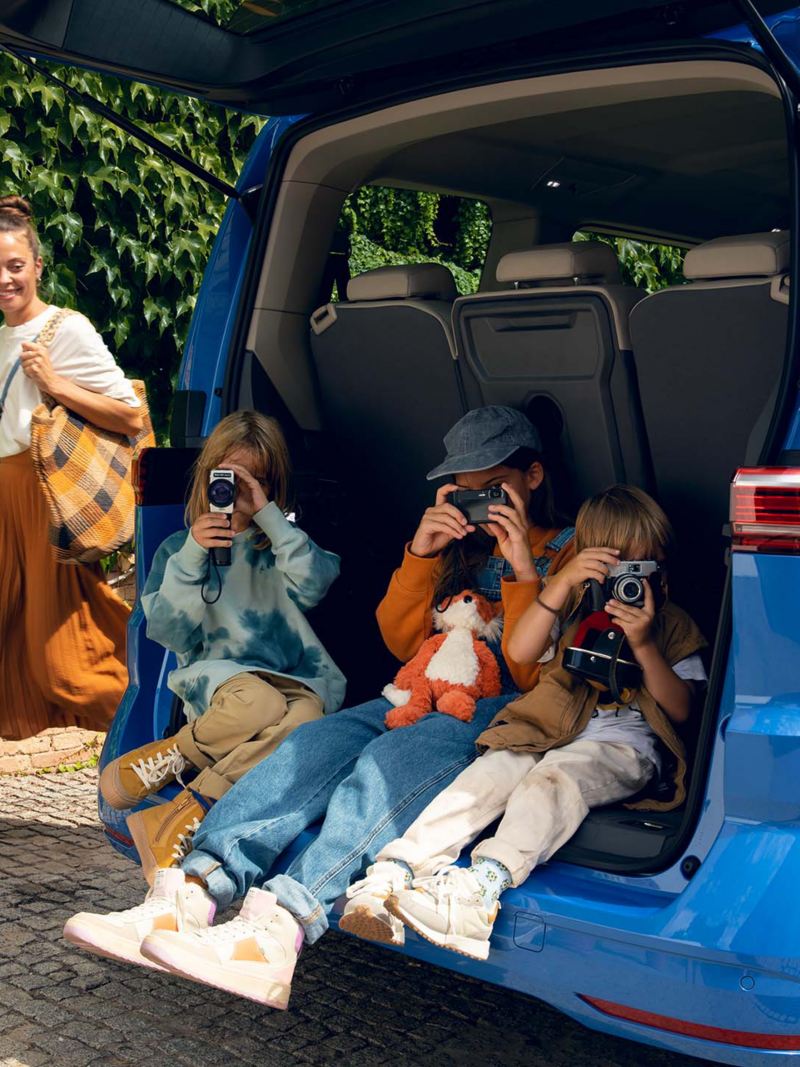 Barn sitter i bagageutrymmet på en blå VW Multivan eHybrid familjebil